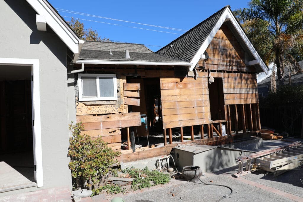 Willow Glen home renovation showing back of house with exterior walls removed and foundation repairs underway.